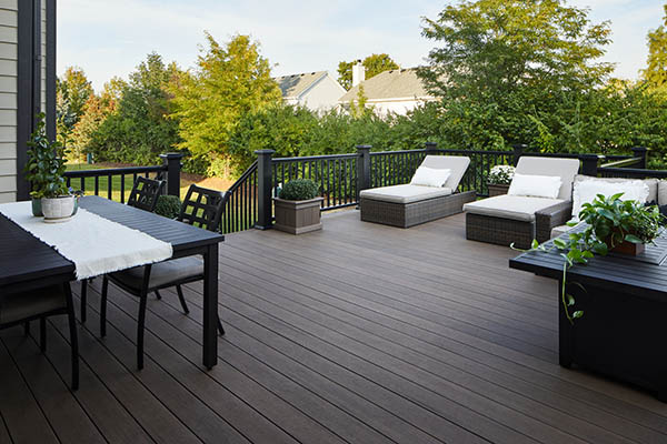 Spacious outdoor deck with modern furniture, comfortable seating, and lush greenery in a serene suburban setting.