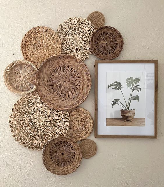 Wall art with woven baskets and a framed plant print, set against a plain white wall for a minimalist decor style.