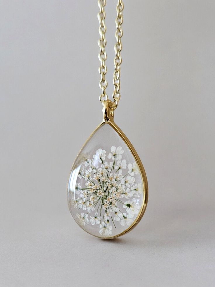 Gold chain necklace with teardrop pendant featuring pressed white flowers, elegant floral jewelry, boho style accessory.