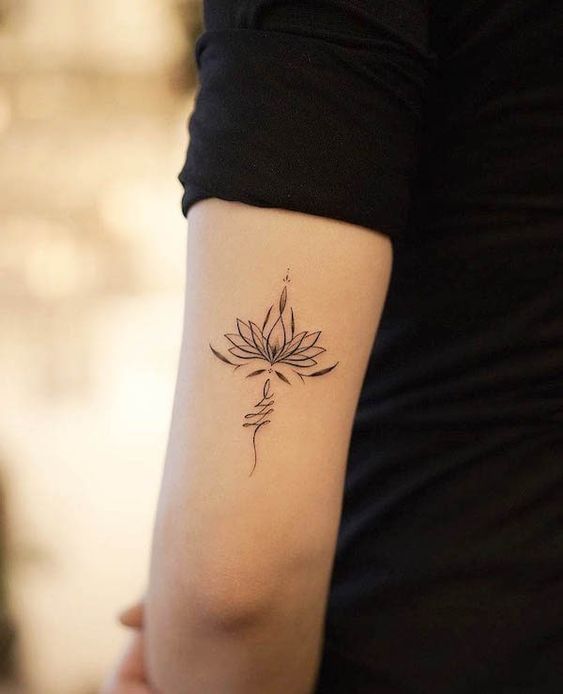 Elegant lotus tattoo on a person's upper arm, symbolizing purity and enlightenment. Simple and stylish body art design.