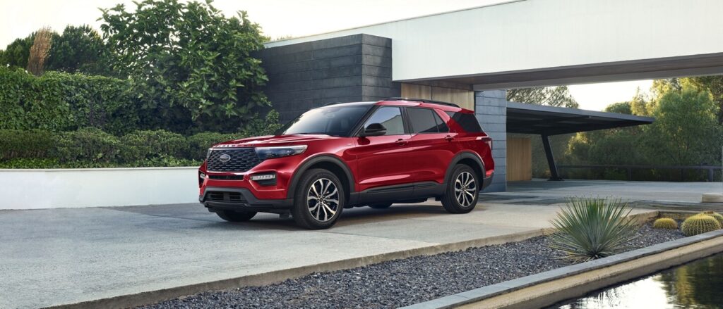 Red SUV parked in front of a modern house, showcasing sleek design and elegant landscaping. Ideal for outdoor adventures.