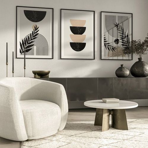 Modern living room with abstract wall art, cozy white armchair, round coffee table, black vases, and minimalist decor.