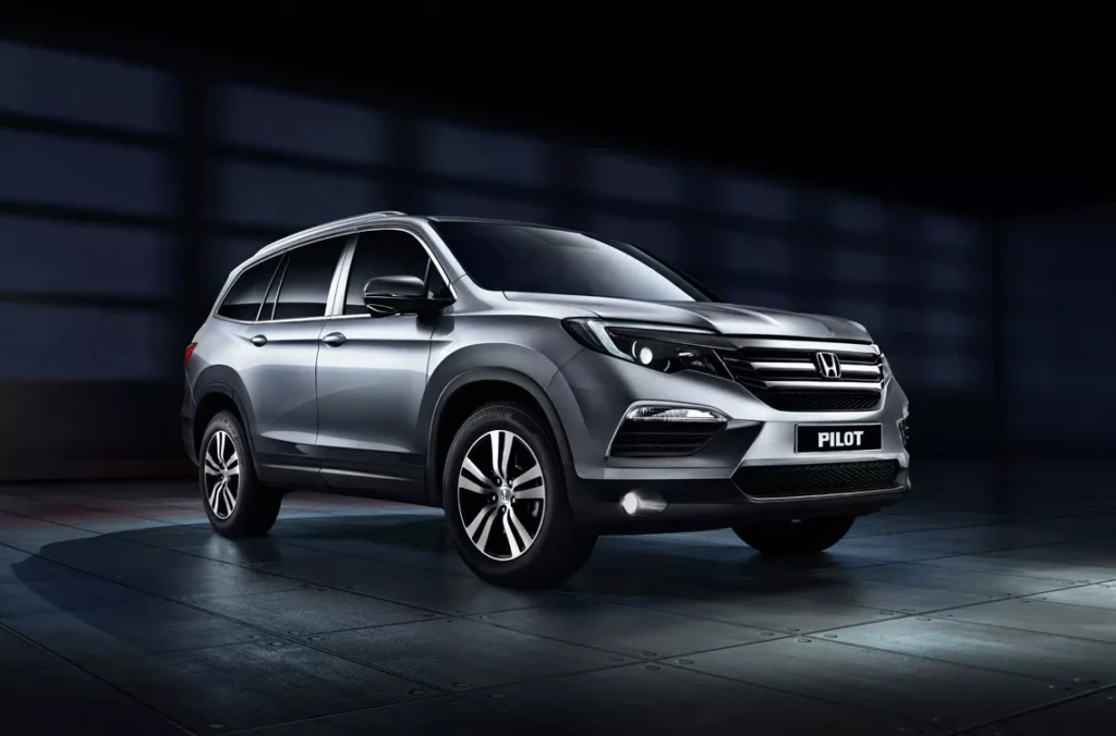 Sleek grey Honda Pilot SUV parked indoors, showing modern design and stylish headlights. Ideal family car.