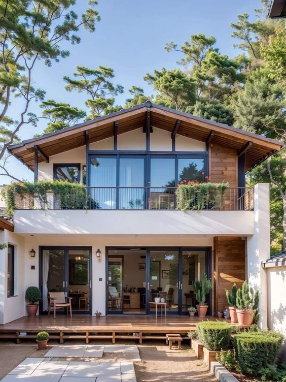 Modern two-story house with large windows, wooden accents, and a spacious front patio surrounded by greenery.