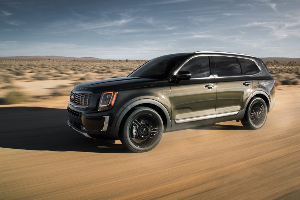 SUV driving fast through a desert landscape under a clear blue sky.