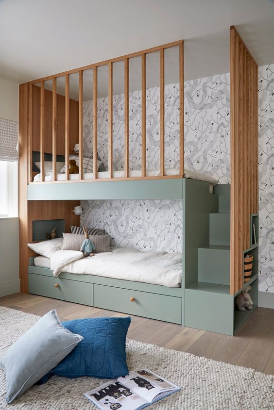 Modern kids' bedroom with green bunk beds, wooden accents, and built-in storage stairs against floral wallpaper. Cozy and stylish design.