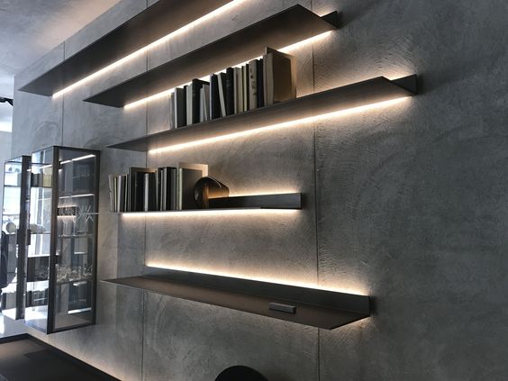 Modern shelf with books and LED lighting against concrete wall in a minimalist interior design setting.