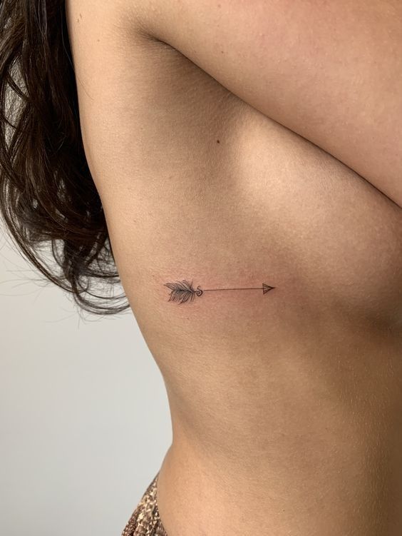 Minimalist side rib arrow tattoo on woman's skin - elegant and simple body art design.