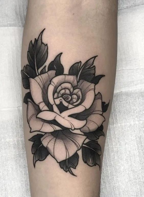 Black and grey rose tattoo design on the inner forearm, featuring detailed petal shading and bold outlines.