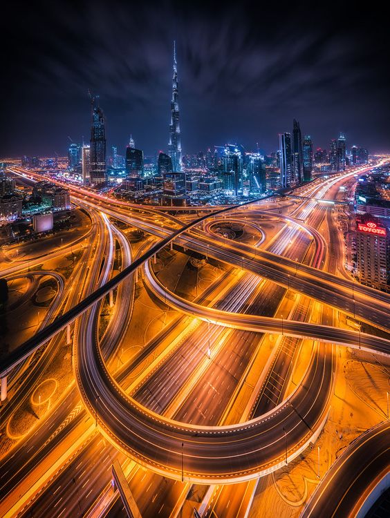 Stunning night view of Dubai's illuminated roads with the towering Burj Khalifa in the backdrop, showcasing urban cityscape.