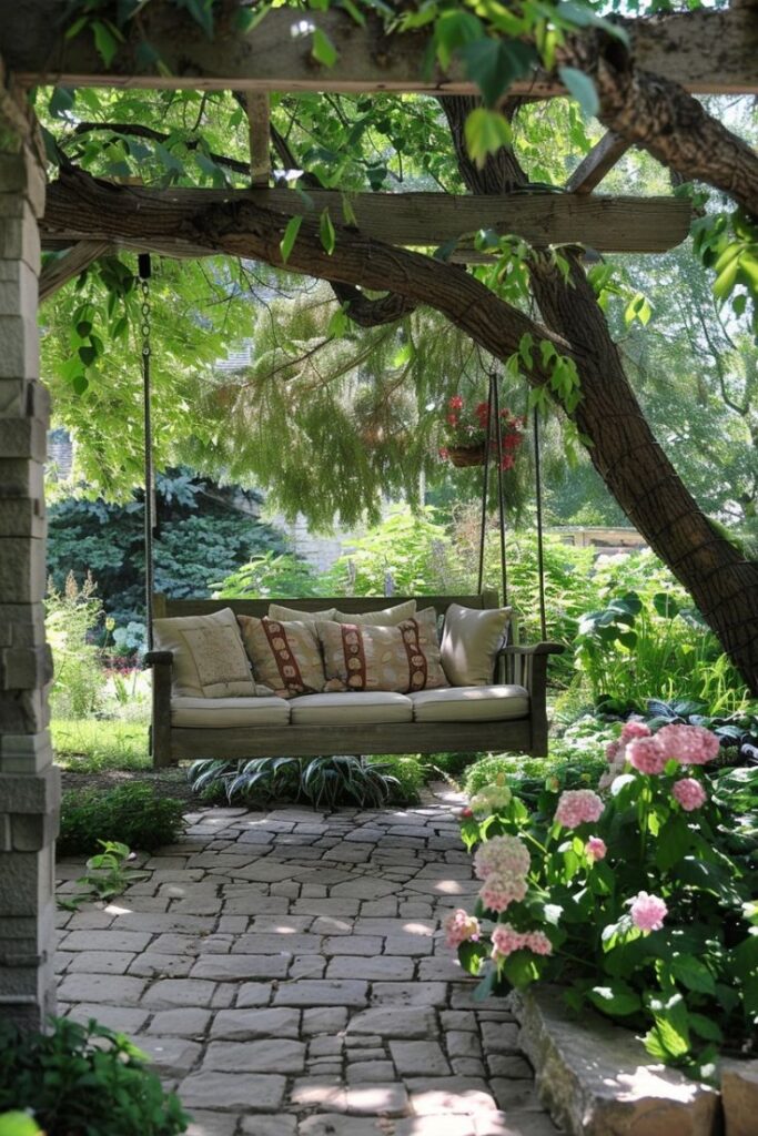 Cozy garden swing adorned with pillows under a pergola, surrounded by lush greenery and blooming pink hydrangeas.