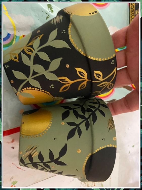 Hand-painted pots with intricate leaf and circular patterns in green, black, and gold, ideal for home decor and gardening.