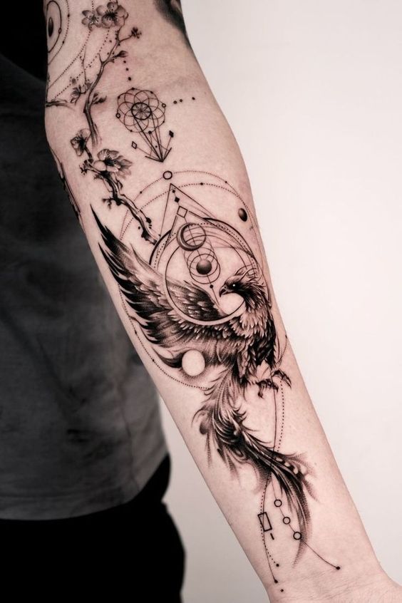 Detailed forearm tattoo of a phoenix with geometric elements and cherry blossom branch; black and grey ink.