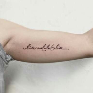 Tattoo on arm reading live and let live in elegant cursive script, highlighting a minimalist and inspirational design.