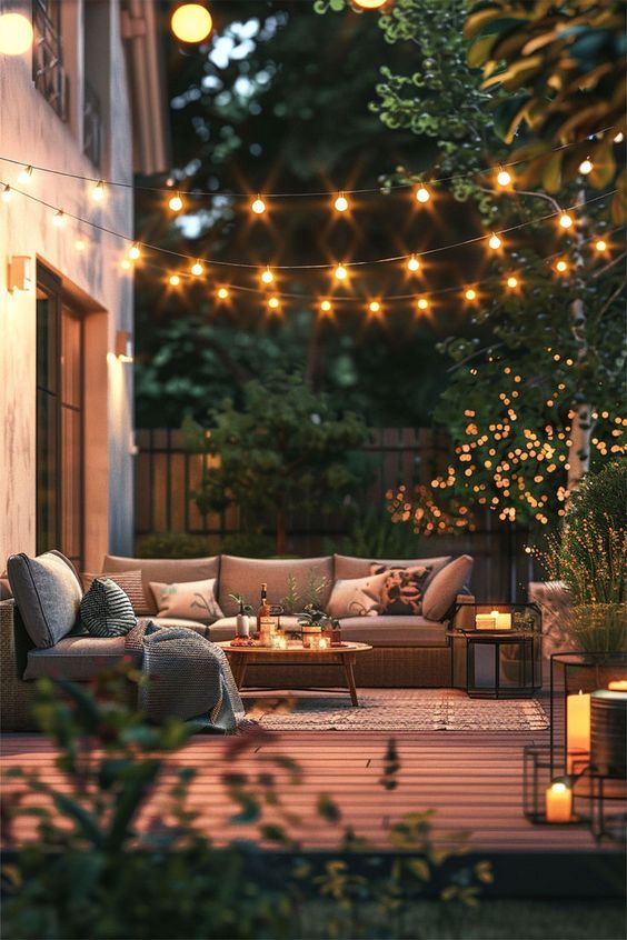 Cozy backyard patio with string lights, comfortable seating, and candles, creating a relaxing outdoor ambiance at dusk.