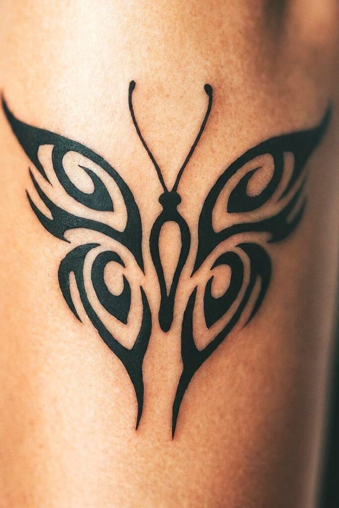 Intricate black tribal butterfly tattoo design on skin, showcasing elegance and symmetry in body art.