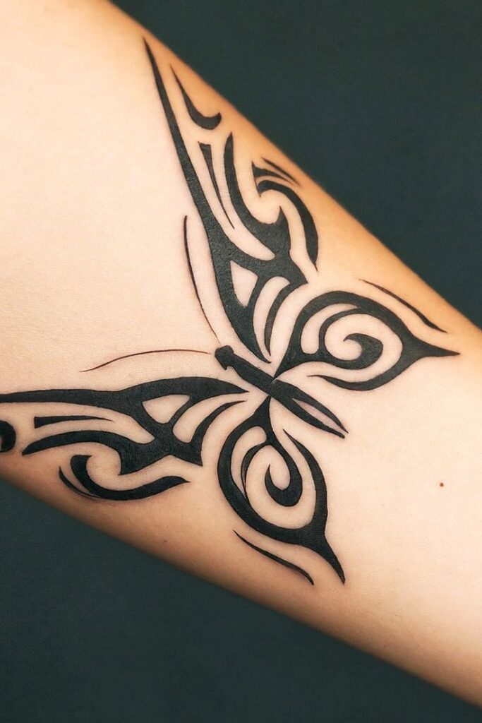 Tribal butterfly tattoo on forearm with intricate black ink design, symbolizing transformation and freedom.