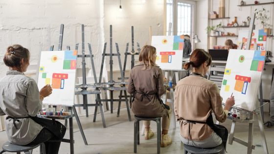 People painting on canvases in an art class, creating colorful abstract designs in a well-lit studio.