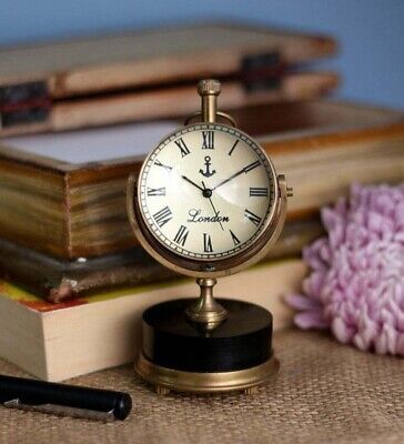 Vintage brass desk clock with Roman numerals, books, and a pink flower. Ideal for classic decor and elegant workspace styling.