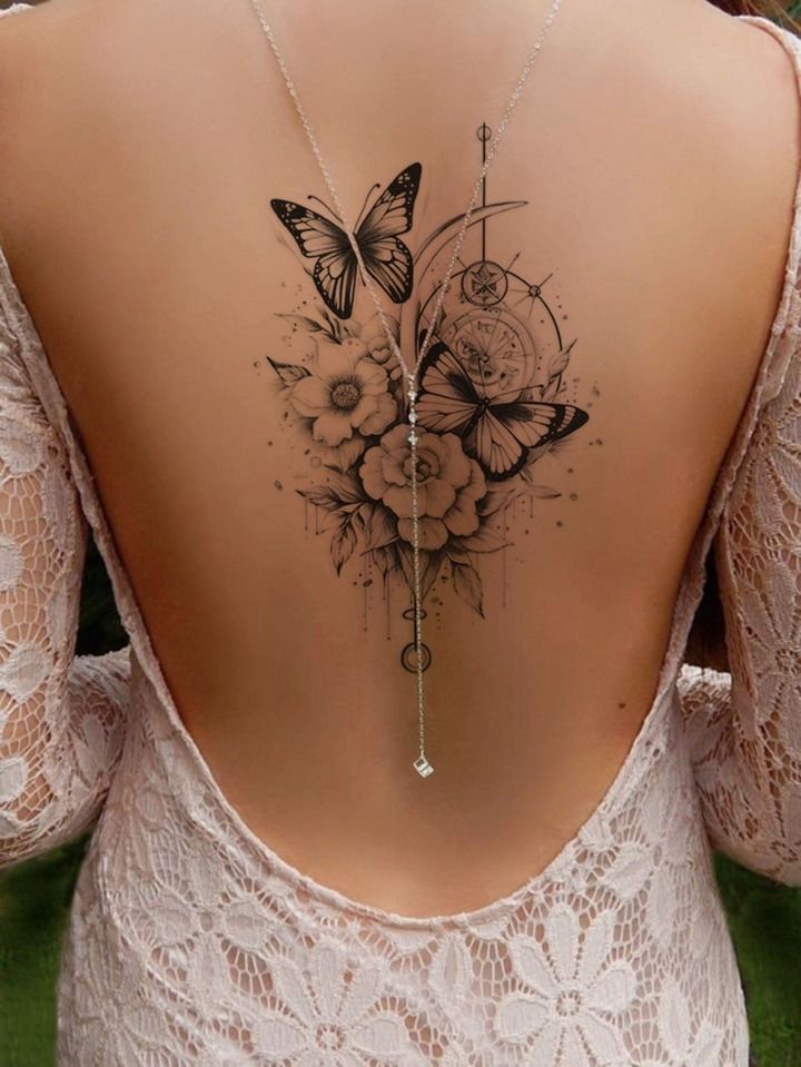 Elegant back tattoo with butterflies and flowers on a woman wearing a lace dress with an open back.