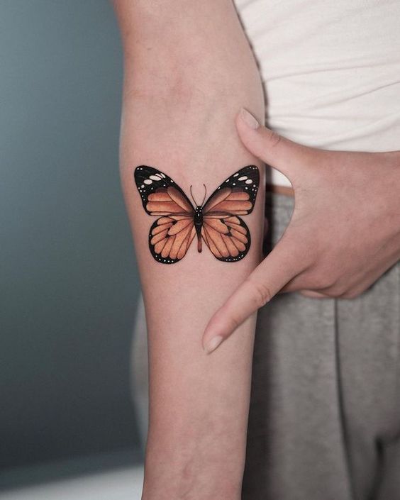 Realistic 3D monarch butterfly tattoo on a person's forearm, showcasing detailed wings and natural colors.