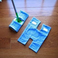 Microfiber mop with two blue reusable cloth pads on a wooden floor, perfect for effective and eco-friendly cleaning solutions.