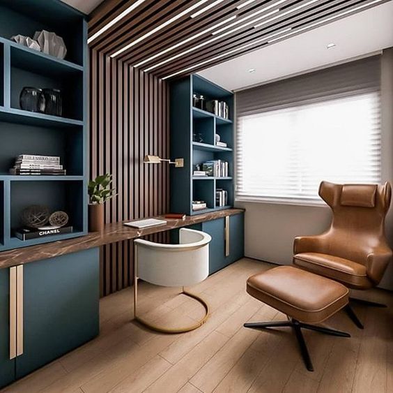 Modern home office with built-in shelves, wooden accents, a leather chair, ottoman, and a large window for natural light.