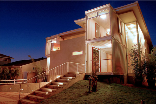 Modern two-story house with illuminated exterior at night, featuring a staircase and large windows.