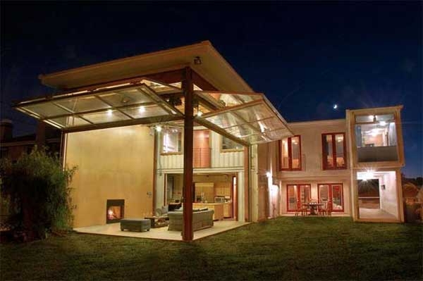 Modern house with glass roof extension and outdoor living space, illuminated at night.