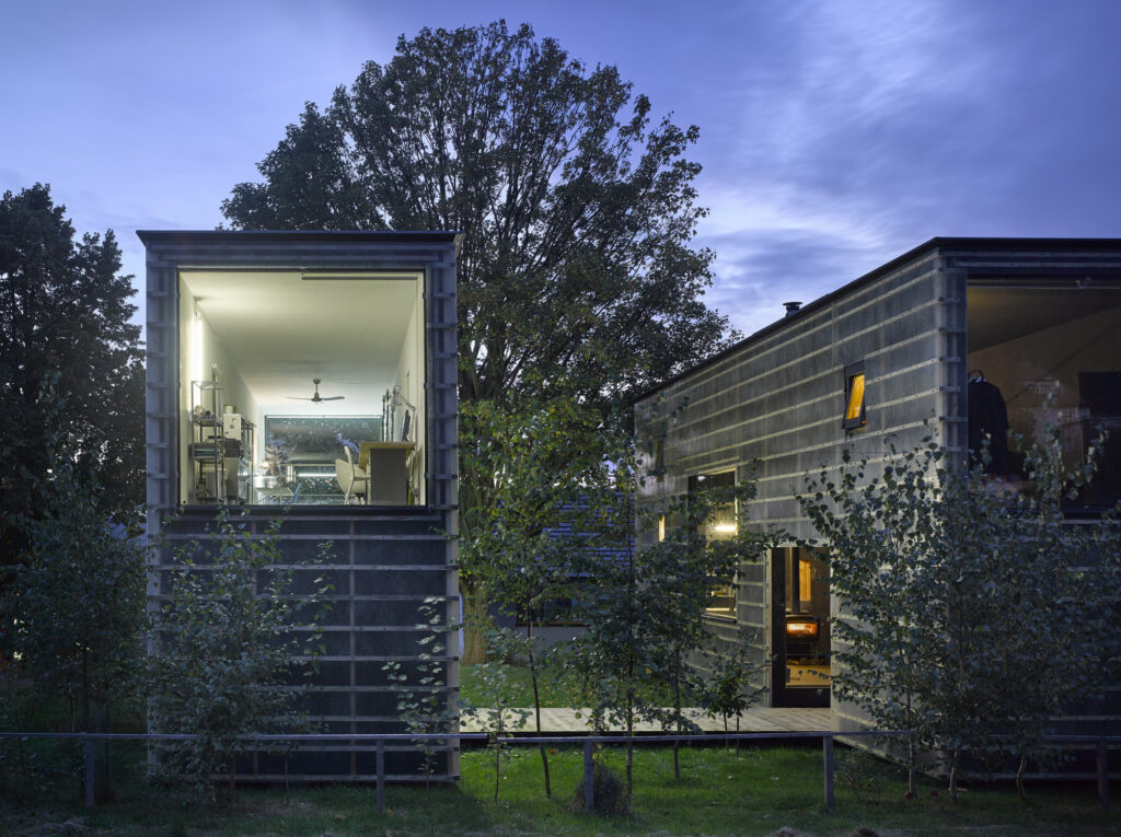 Modern cantilevered container houses in a lush green setting during twilight, showcasing innovative design and natural light.