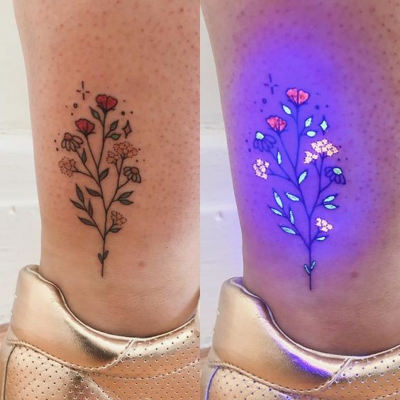 Floral tattoo with UV light effect, showing colorful flowers on skin, glowing under black light. Unique body art design.