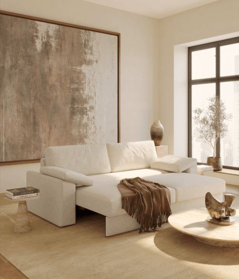 Modern living room with beige sofa, abstract wall art, large window, coffee table, and neutral decor elements.