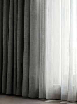 Elegant dark and light curtains in modern home, showcasing gradient textile design against soft filtered natural light.