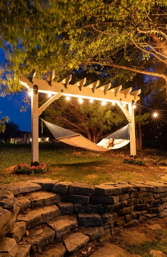 Cozy hammock under pergola lights at night in a tranquil garden retreat. Perfect spot for relaxing and enjoying nature.