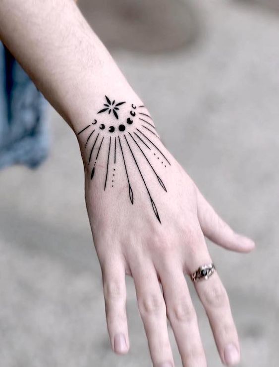 Geometric sun and moon phases tattoo on forearm with rays and dots, minimalist design, black ink, modern body art.