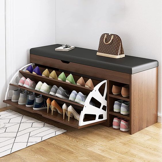 Wooden shoe storage bench with black cushion, open shoe racks, and shelf; handbag placed on bench top in modern room.