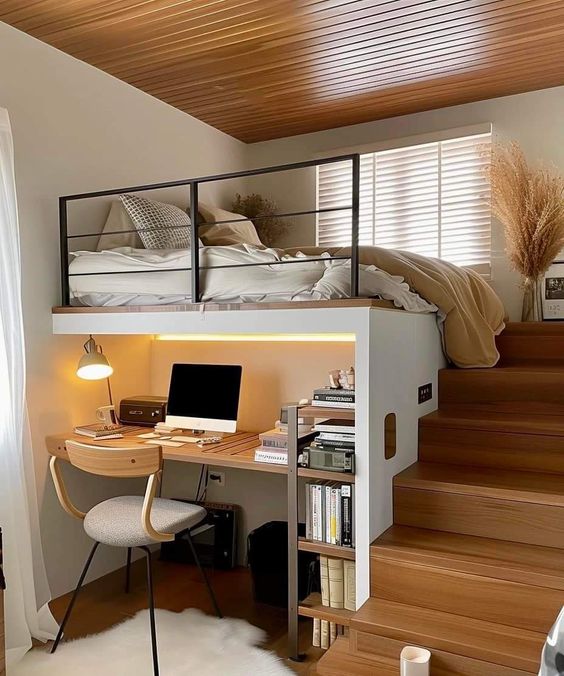 Modern loft bed with cozy workspace below, featuring a computer, books, and a wooden staircase with minimalist decor and lighting.