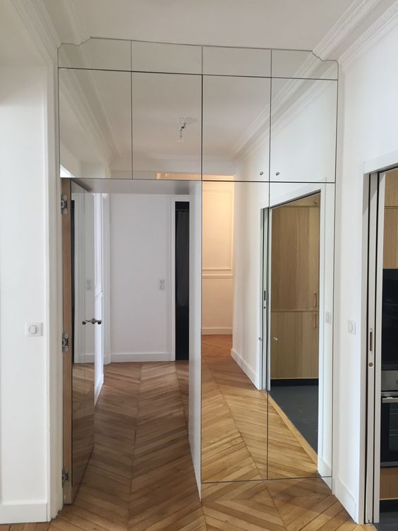 Modern hallway with mirrors and wooden parquet flooring in a contemporary home interior design setting.