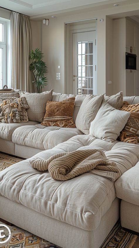 Cozy living room with beige sectional sofa, patterned pillows, and a knitted throw blanket, set against a neutral-toned background.