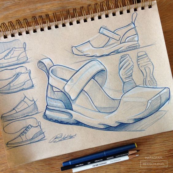 Shoe design sketches in a sketchbook featuring various sneaker styles, drawn with blue pencil, and a pair of pens on the side.