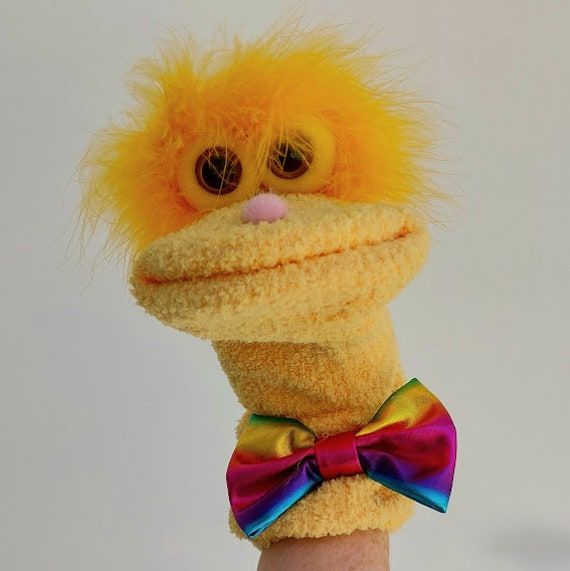 Yellow fuzzy puppet with a colorful bow tie against a plain background, perfect for children's entertainment and shows.