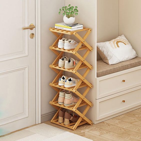 Elegant wooden shoe rack in entryway with neatly organized shoes and a potted plant on top, next to a cozy bench with cushion.