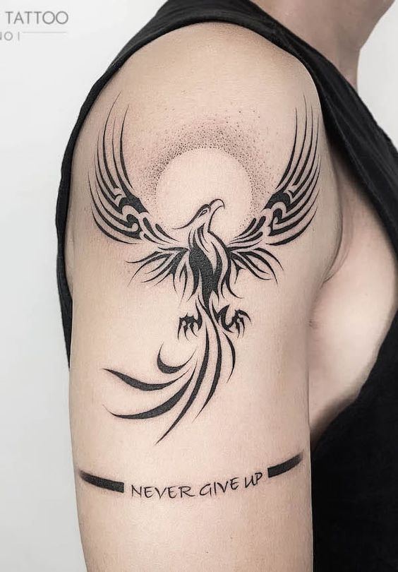 Phoenix tattoo on upper arm with Never Give Up text, symbolizing strength and resilience. Black ink, soaring bird design.