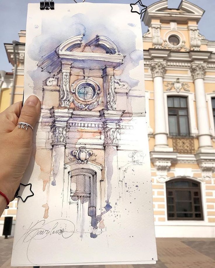 Hand holding a detailed architectural sketch in front of the real building, blending art with reality.