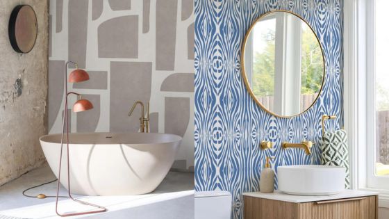 Modern bathroom with freestanding tub, abstract wall art, round mirror, blue patterned wallpaper, and stylish fixtures.