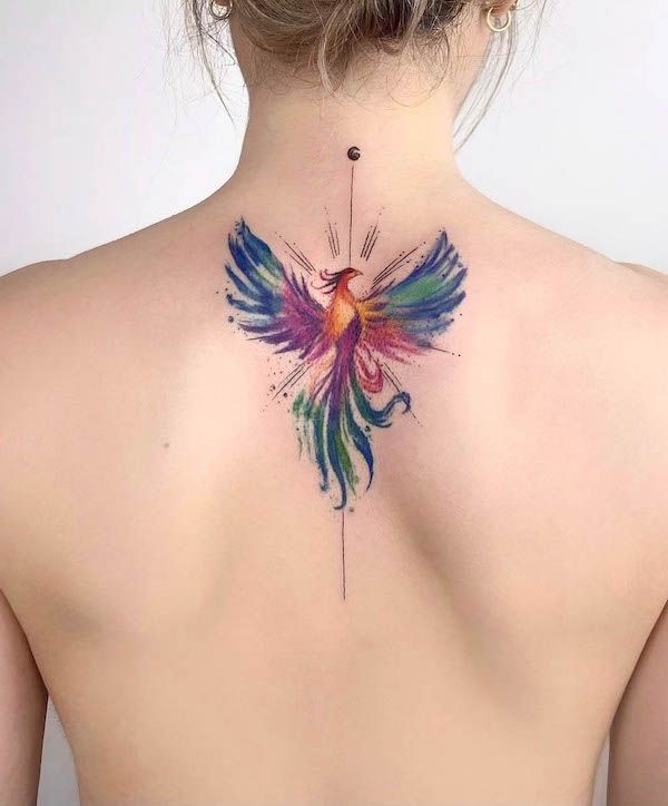 Close-up of a colorful phoenix tattoo on an upper back, symbolizing rebirth and strength in vibrant watercolor style.