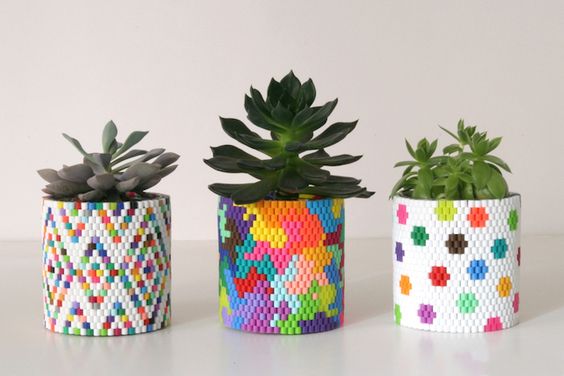 Three colorful, beaded planters with succulents on a white background, showcasing creative and vibrant plant pot designs.