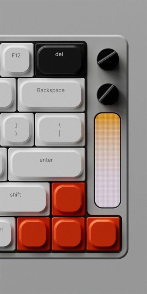 Close-up of a modern mechanical keyboard with white, black, and orange keys and dual control knobs on a grey panel.