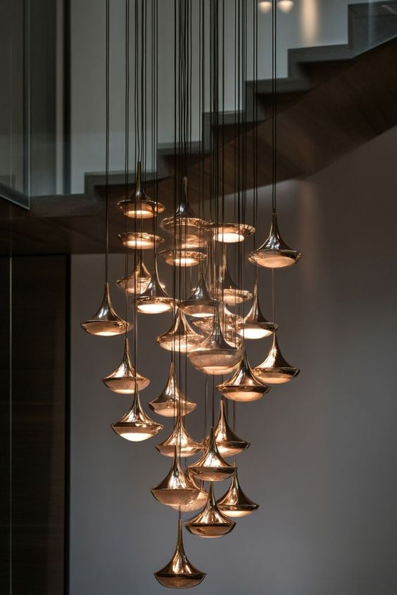 Modern luxury pendant chandelier with multiple hanging lights, illuminating a stylish staircase in a contemporary home.