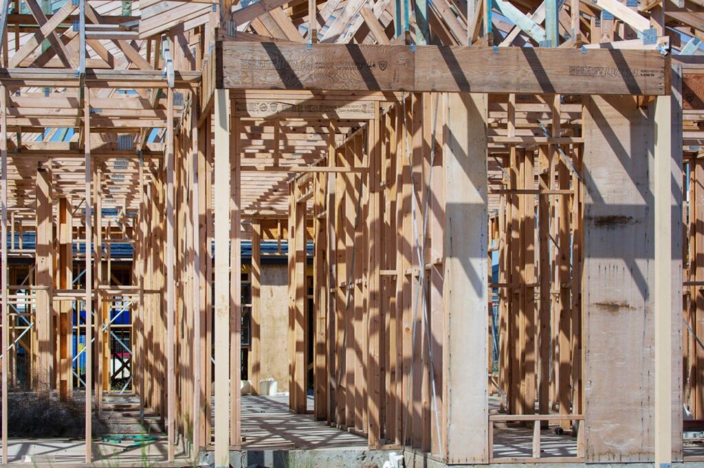 Wooden house frame construction site. Building a new home with wooden beams and supports. Residential construction progress.